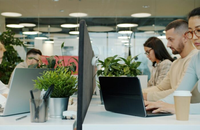 Zone & Co brings hundreds of projects into Smartsheet Control Center, improving visibility and saving hours weekly per manager 1 coworkers in an office looking at computers